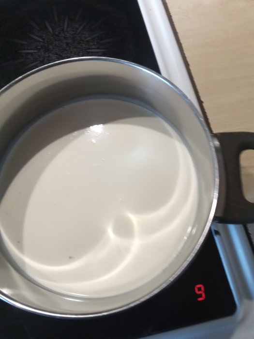 Grädde i en kastrull på spisen redo för att vispa ihop till flötgröt.