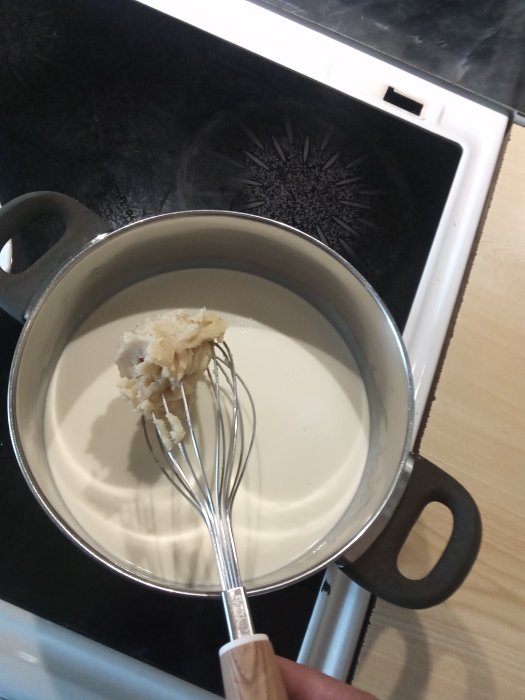 Tillagning av flötgröt i kastrull med visp på spishäll.