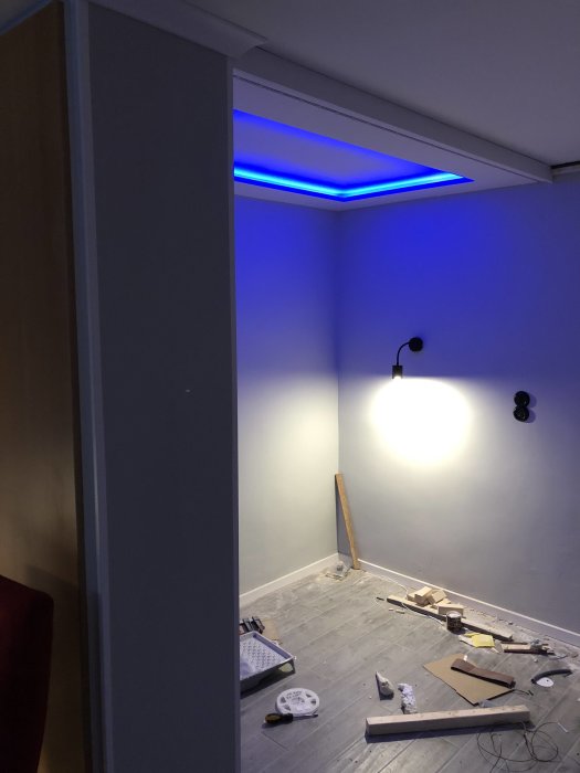 Renoveringsrum med blått LED-ljus i innertak och diverse byggmaterial på golvet.