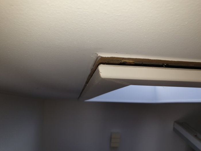 Öppning mellan takfönstersmyg och innertak som visar en växande spricka, inga vattenskador synliga.