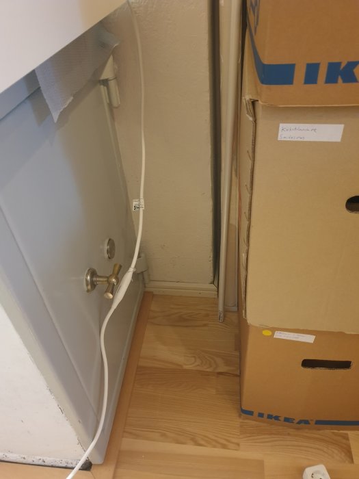 Eluttag och kablar vid ett 3d-printer-skåp med oordnade kablar och en IKEA-kartong.