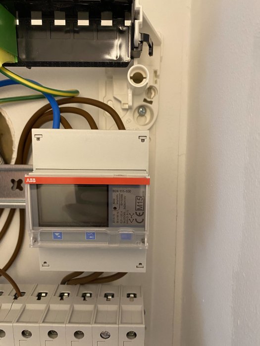 Inre delen av ett elskåp med öppen framsida och synlig elektronik inklusive en ABB energimätare.