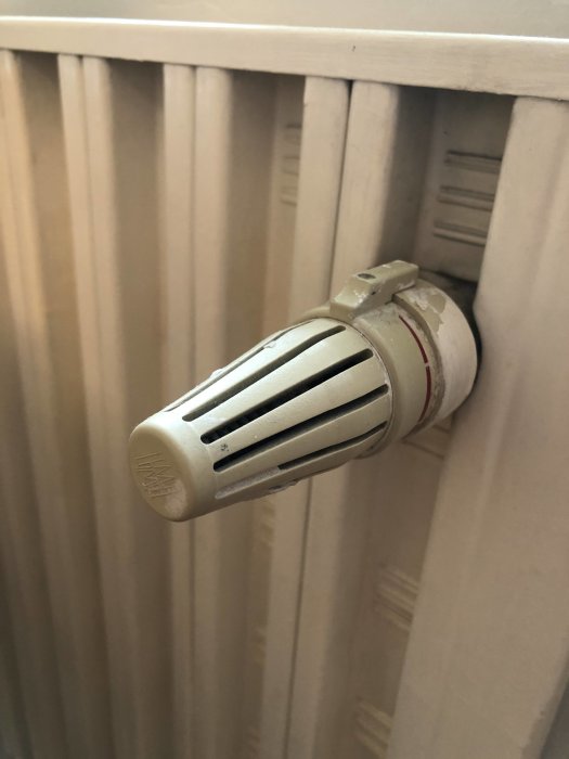 Gammal radiator med vit termostatventil från 60-talet som behöver nya vred.