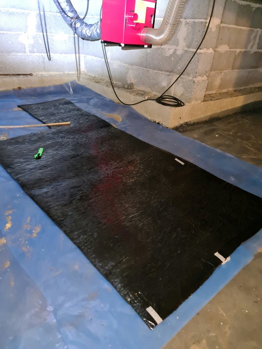 Krypgrund med synliga jordvärmerör, avfuktare och isoleringsmaterial.