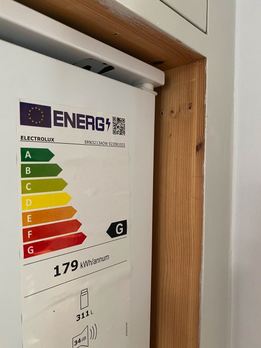 Närbild på en Electrolux kylskåpsmodell ERN3213AOWs energimärkning och del av dörren.