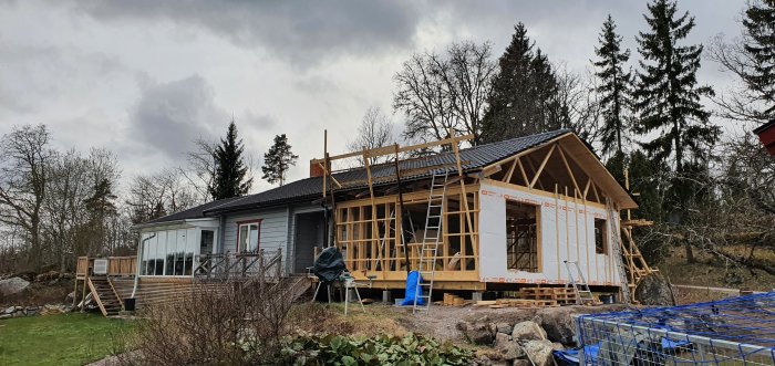 Takläggning på hus under konstruktion med nästan färdiga takpannor och sista raden som behöver kapas.