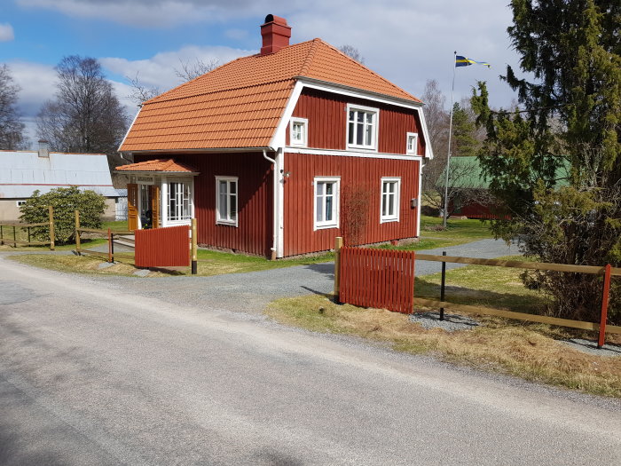 Typiskt rött svenskt hus med vit knut och torkställning med ribbor.