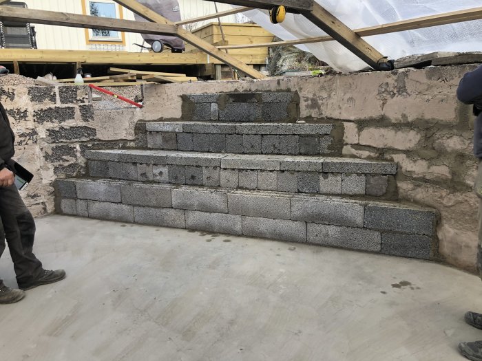 Nybyggda trappsteg i gråa betongblock för pool, med en person som står bredvid.