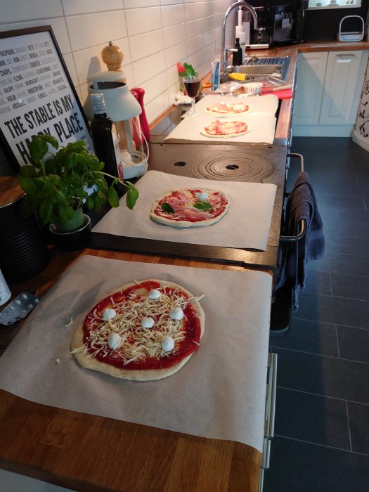 Opreparerade pizzor på köksbänk med olika fyllningar redo för gräddning.