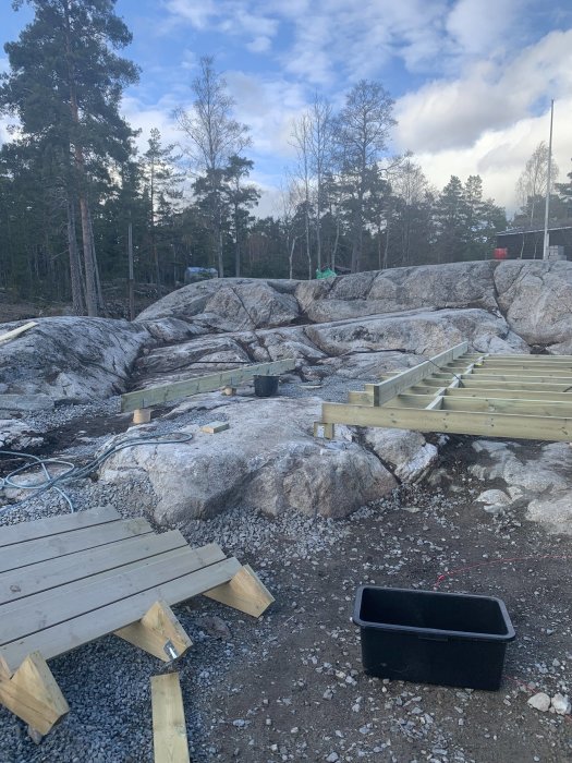 Byggplats med uppmätt virke och bärlina, klart väder med stundande byggnation på halvfart p.g.a. snöfall.