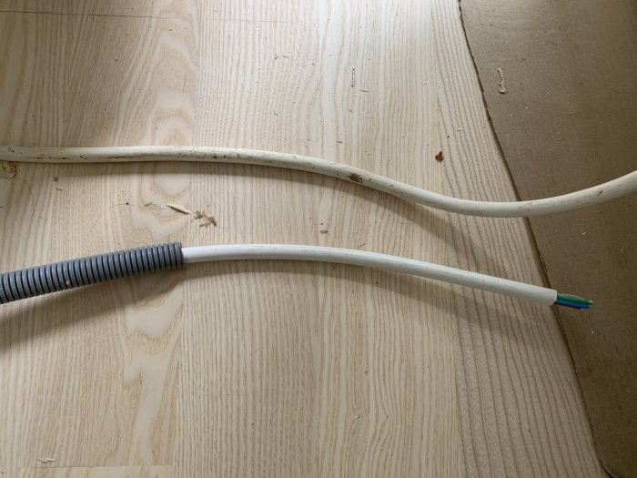 Elektrisk kabel för trefasmatning ligger på ett trägolv, redo för framtidens anslutning.
