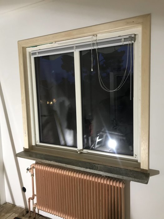 Fönster med nyligen fräst och installerat träfoder ovanför en radiator.