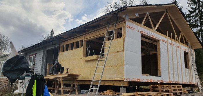 Hus under renovering, nytt tak och vindpapp, person arbetar på altanen.