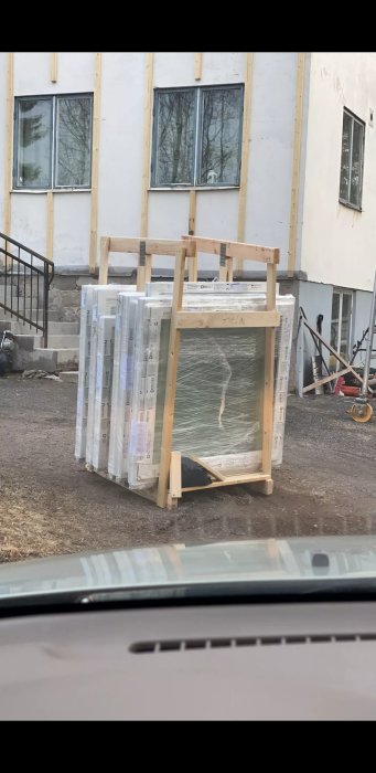 Nyförpackade fönster i träramar redo för installation vid en byggplats.