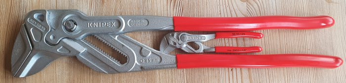 KNIPEX tång i metall med röda handtag och vit text, storleksmärkt 250 mm, på ett träunderlag.