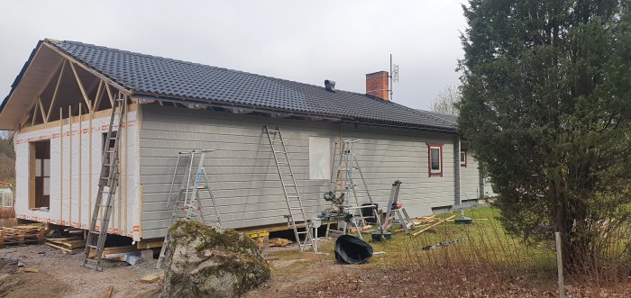 Renoverat hus med nyligen monterad träpanel och byggstegar runtomkring.