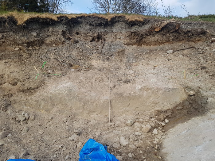 Uppgrävd slänt med en 70 cm hög bergsavsats används för att överväga konstruktion av en suteräng eller mur.