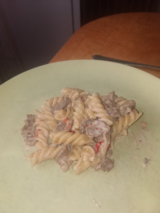 En tallrik med pastarätt innehållande lövbiff, paprika, lök i gräddig sås, nära färdig att ätas.