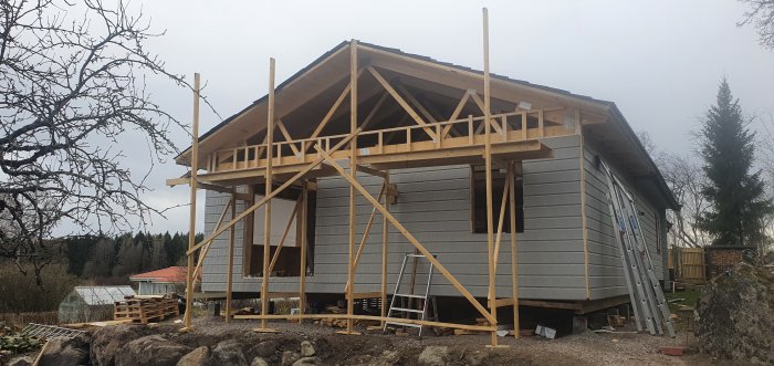 Hus under renovering med ofullständig byggnadsställning och saknade räcken och snedsträvor.