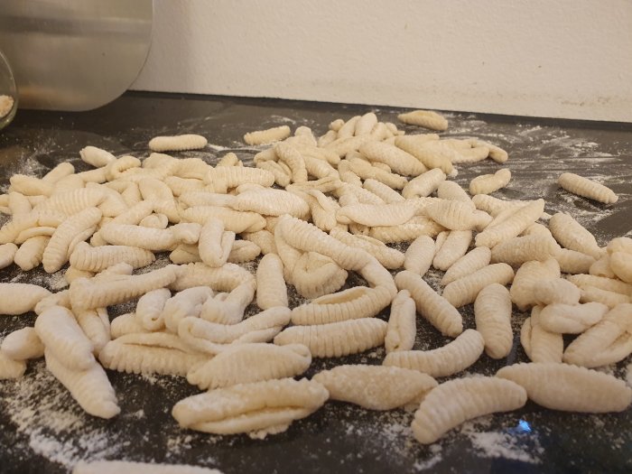 Hemgjord Cavatelli pasta strösslade med mjöl på ett köksbord.