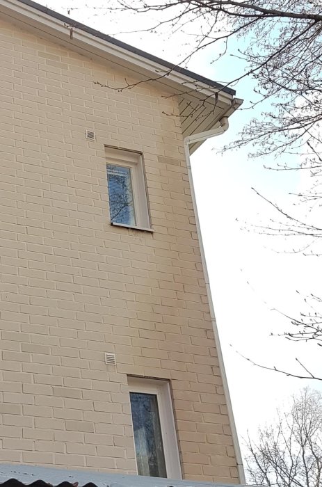 Hus hörn med tegelfasad där några tegelstenar ser mörkare och våta ut, möjlig fuktskada nära stupränna.