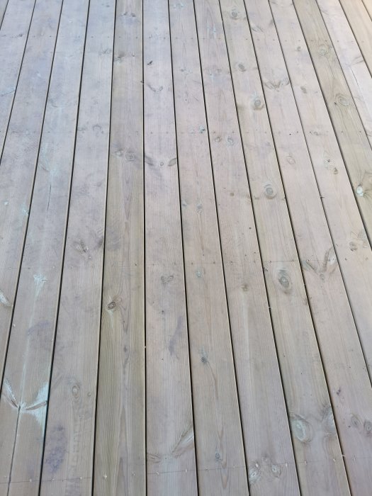 Närbild på trädäck med varierande bredd på springorna mellan brädorna.
