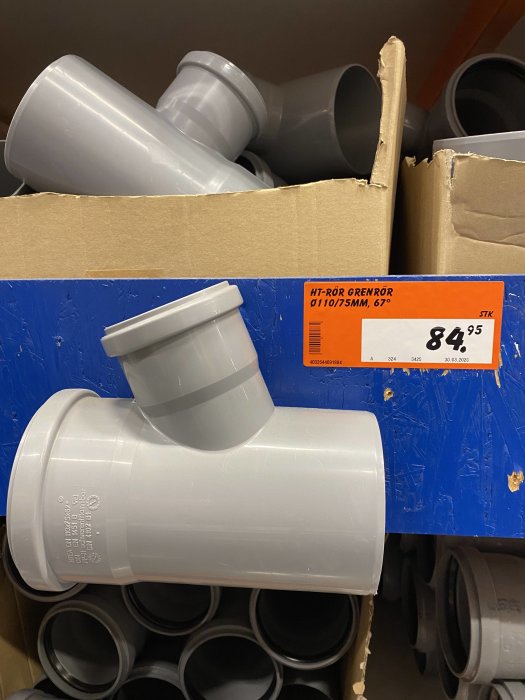 Grå HT-rörgrenrör av plast med texten "HT-RÖR GRENÖR Ø110/75mm, 67°" och prislapp i en kartong.