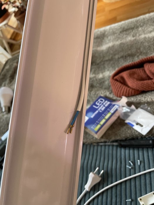 Exponerade elektriska ledningar på en rosa yta med byggmaterial i bakgrunden.