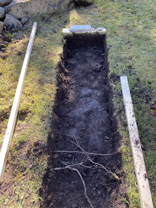 Grävd 70cm bred grund för platta, planerad att stödjas av makadam och markduk, innan gjutning.