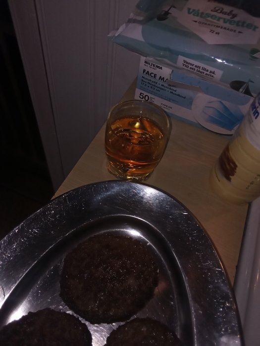 Hamburgare på en bricka bredvid ett glas whisky och en förpackning våtservetter.