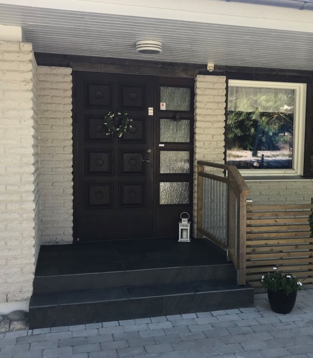 Renoverad entrétrappa klädd i mörk dansk Sjösten med vitmålade husväggar och brun dörr.