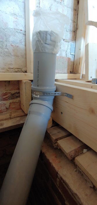 Nyinstallerat avloppsrör i PVC med hålband för fixering i en badrumsrenovering.