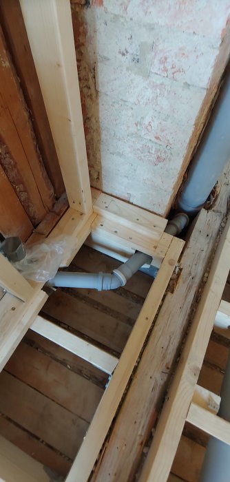 Nyinstallerade avloppsrör i träregelverk vid badrumsrenovering, väntar på fixering och flytspackel.
