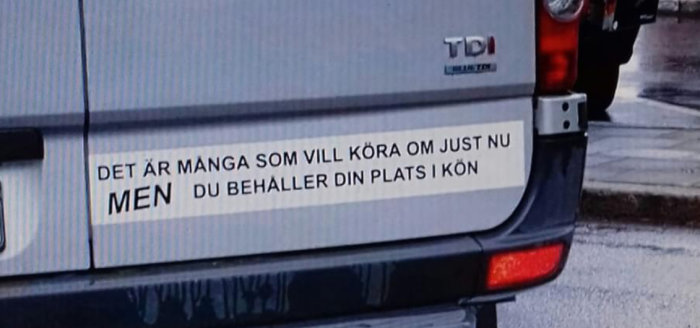 Bakdel av en bil med textdekal som lyder "DET ÄR MÅNGA SOM VILL KÖRA OM JUST NU MEN DU BEHÅLLER DIN PLATS I KÖN