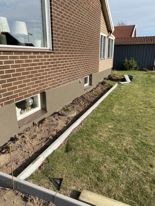 Kantsten som sätts vid husgrund för framtida rabatt, gräsmatta och utedekor syns.