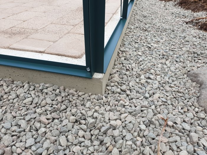 Nyinstallerat växthus med tröskelfri ingång och stenplattor i nivå med växthuset på grusunderlag.