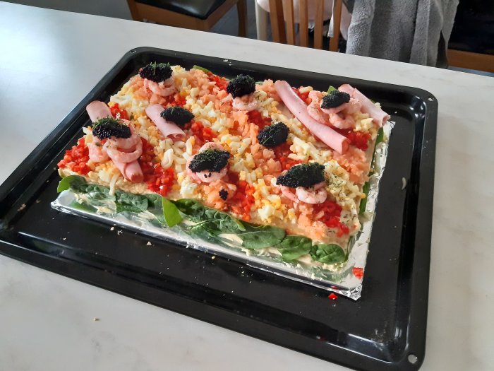 Olagad pizza på en ugnsplåt med räkor, skinka, kaviar och grönsaker.