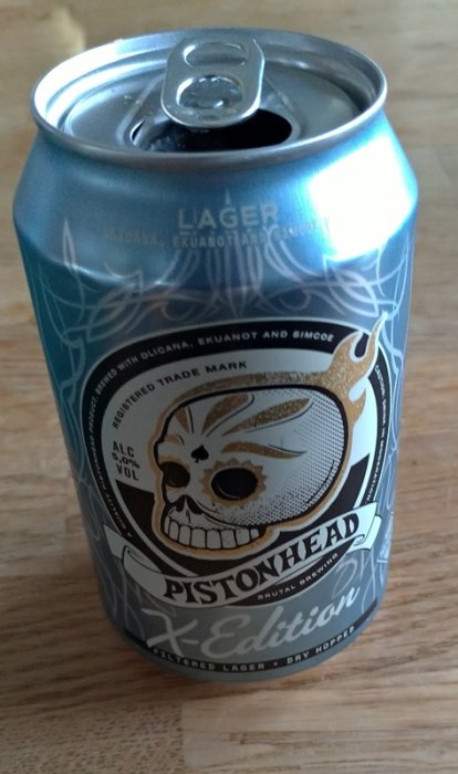 Öppnad ölburk av märket Pistonhead med distinkt design med dödskalle och text, antydan om citrus-smak.