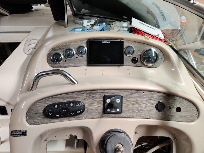 Båtens styrpanel med instrument och kontroller, renoverad med ny panel i vinylgolvsmaterial.