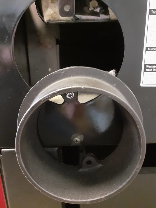 Vit lock används för att täcka sidorökutgång på en svart kamin, fäst med två skruvar och runt eldfast garn.