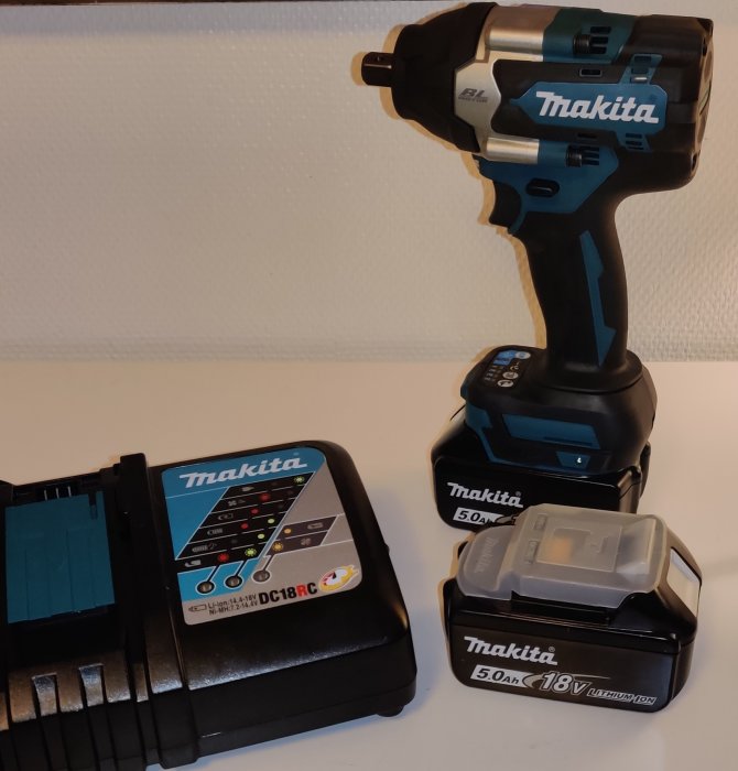 Makita DTW701RTJ slagskruvdragare med batteri och laddare på ett bord.