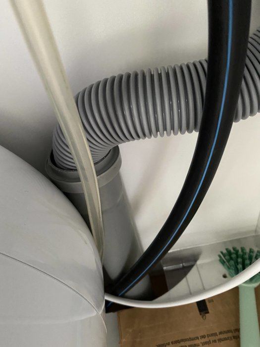 Flexibelt avloppsrör anslutet till köksdisk, med en synlig storleksövergång och andra rör i bakgrunden.