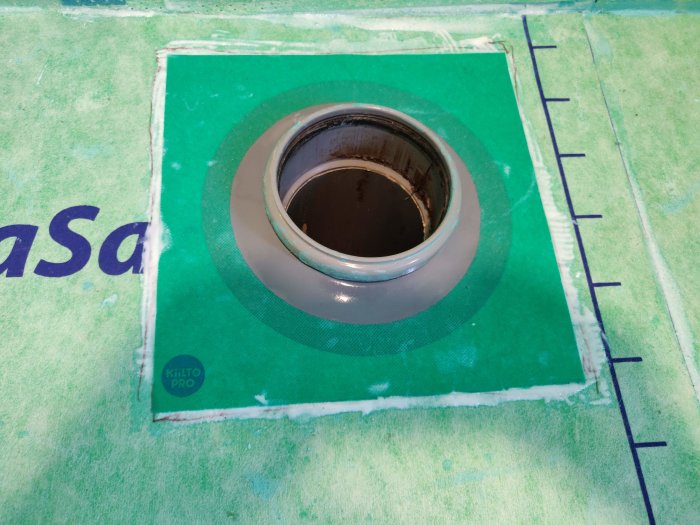 Nyinstallerad brunnsmanschett på tätskikt i badrum med synligt Kiilto Pro-märke och måttmarkeringar.