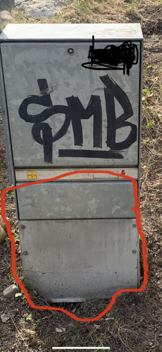 Graffitimålad gatukabelskåp med en röd cirkel markerad runt underdelen där kablar går in i marken.