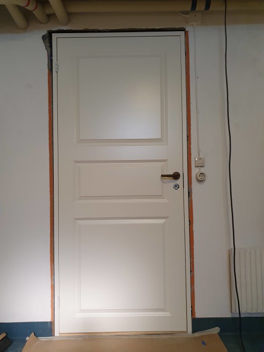 Vit innerdörr från Diplomat som hänger snett i en välinstallerad dörrkarm.