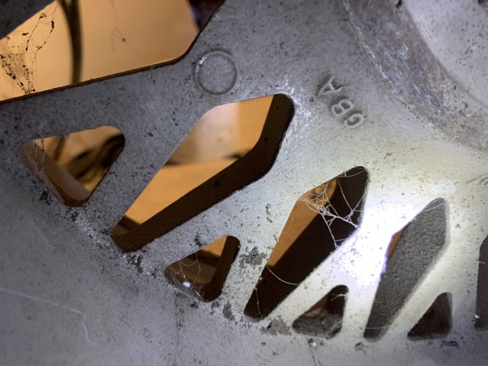 Närbild på smutsigt däck med synlig texten "8Jx" och spindelnät i fälgen.