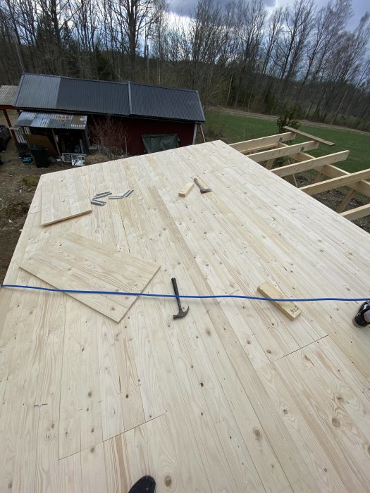 Nyligen spikat råspont och underlagspapp på ett tak med verktyg synligt.