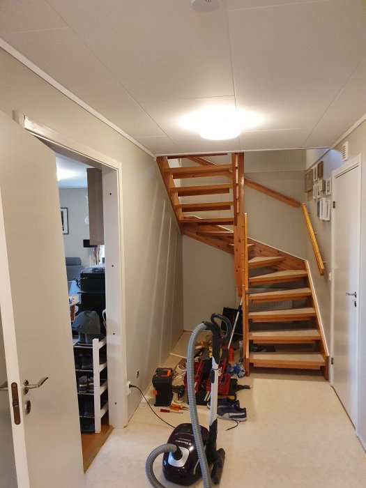 Trappa i hemmiljö med verktyg och målarmaterial utspritt på golvet under renovering.