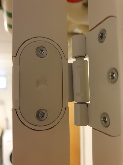 Närbild av en dörrkarm med ett övre dörrgångjärn som inte sitter fast ordentligt, vilket kan vara ett fel.