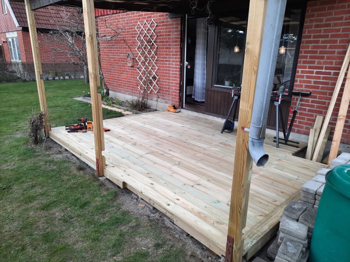 Nybyggd trädäck på en bakgård med minimalt spill och verktyg synliga.